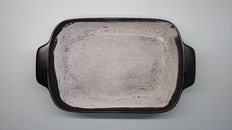 Pekáč na pečení vysypaný hrubou moukou a vymazaný olejem