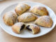 Domácí pečené povidlové taštičky z křehkého máslového těsta, posypané moučkovým cukrem, s viditelnou švestkovou náplní.